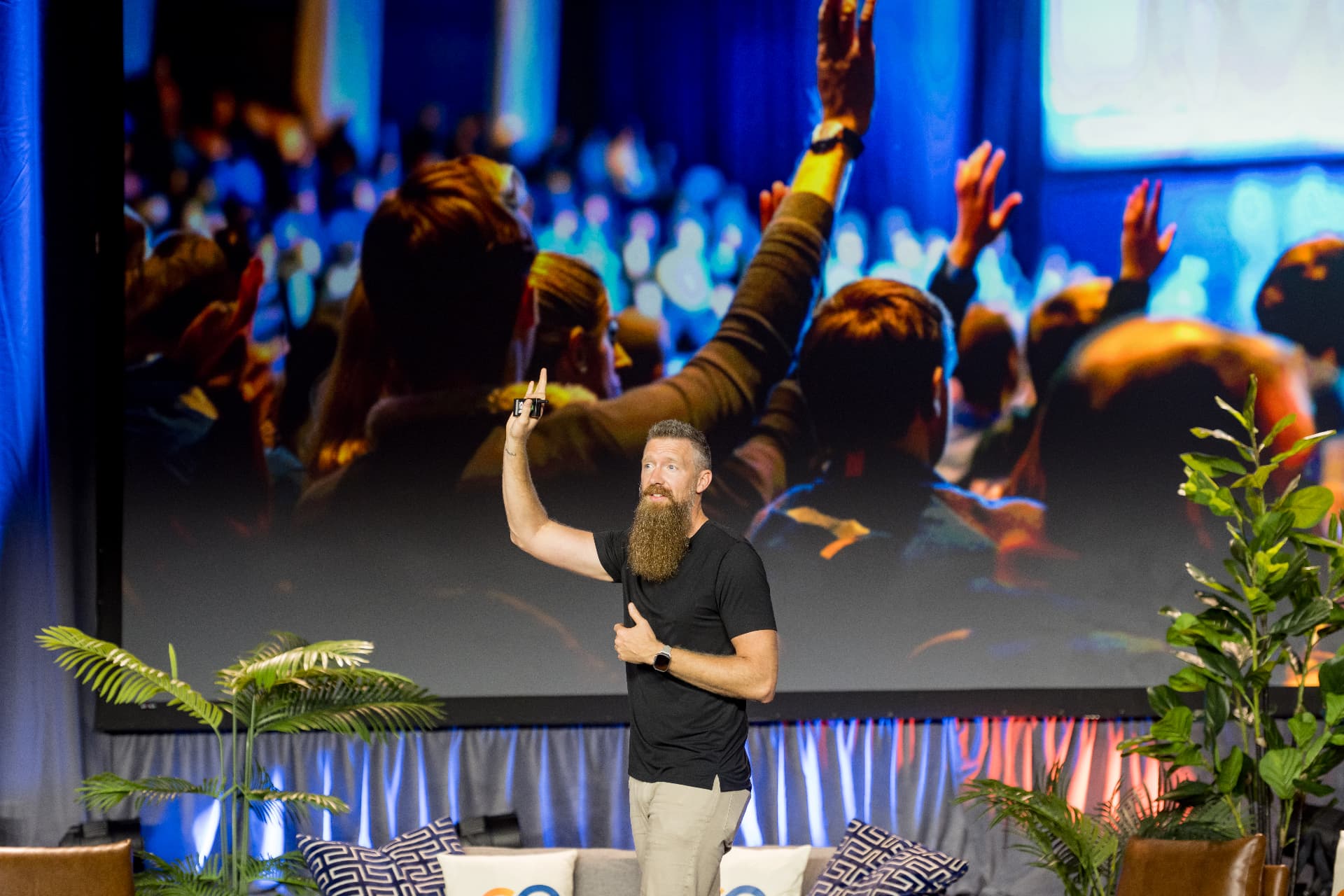 Speaker on stage with an engaged audience raising hands at a corporate event in Dallas, Texas